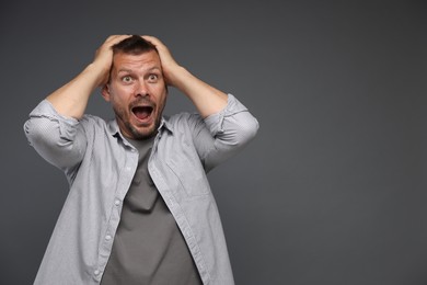 Photo of Man suffering from panic attack on grey background, space for text