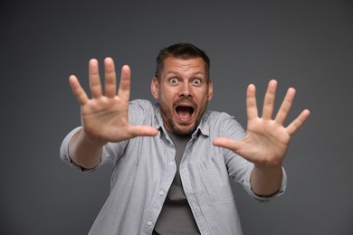 Photo of Man suffering from panic attack on grey background