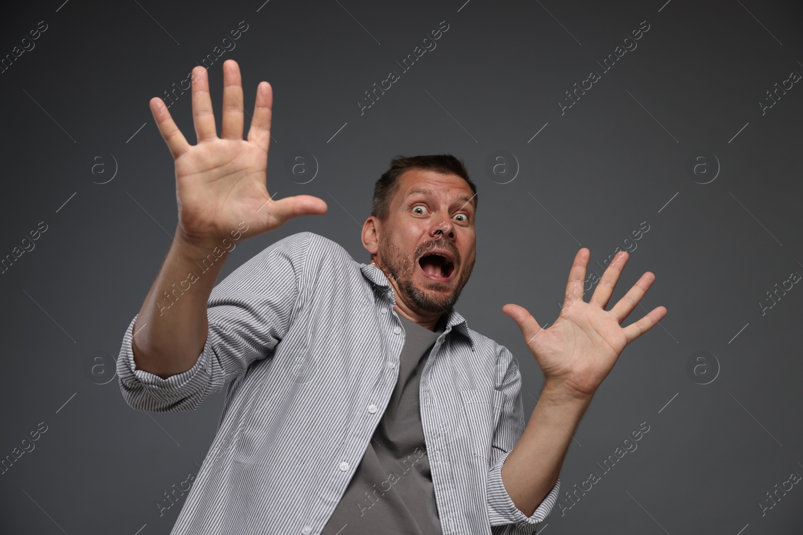 Man suffering from panic attack on grey background Photo of Man suffering from panic attack on grey background