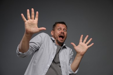 Photo of Man suffering from panic attack on grey background