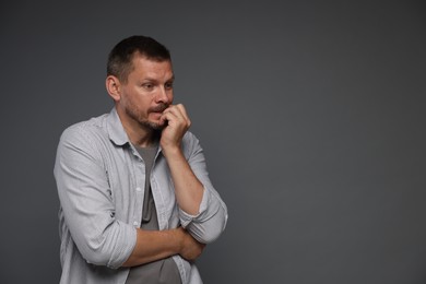 Photo of Man suffering from panic attack on grey background, space for text