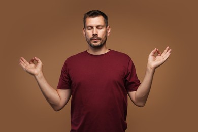 Photo of Panic attack. Man meditating to calm down on brown background