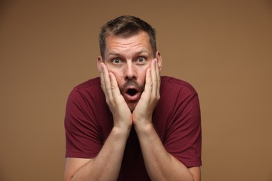 Photo of Man suffering from panic attack on brown background