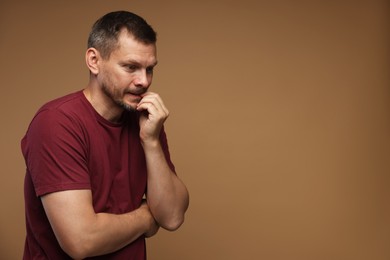 Photo of Man suffering from panic attack on brown background, space for text