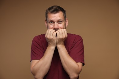 Photo of Man suffering from panic attack on brown background