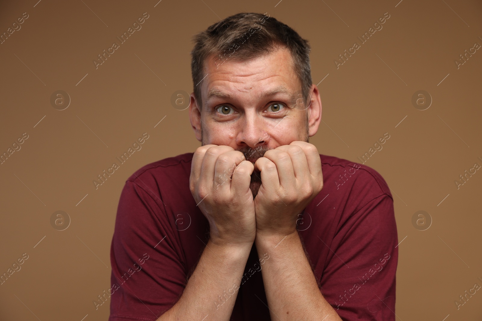 Man suffering from panic attack on brown background Photo of Man suffering from panic attack on brown background
