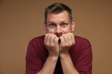 Photo of Man suffering from panic attack on brown background