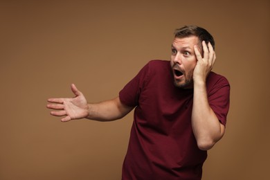 Photo of Man suffering from panic attack on brown background