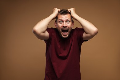 Photo of Man suffering from panic attack on brown background