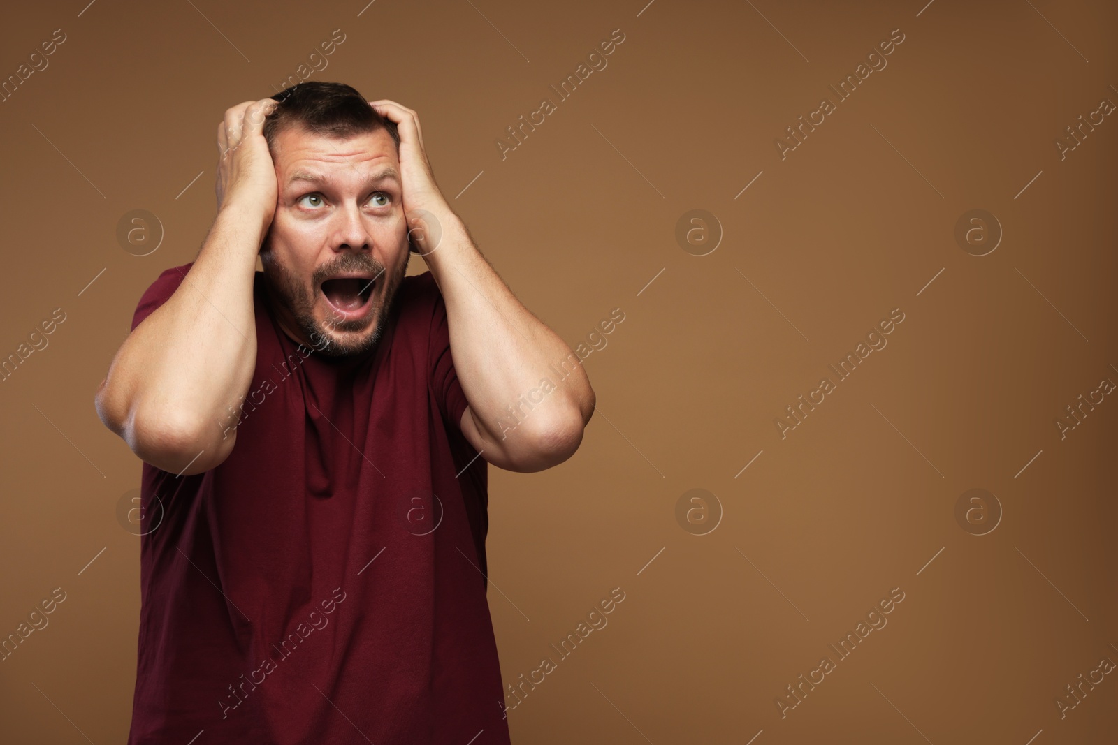 Man suffering from panic attack on brown background, space for text Photo of Man suffering from panic attack on brown background, space for text