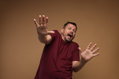 Photo of Man suffering from panic attack on brown background