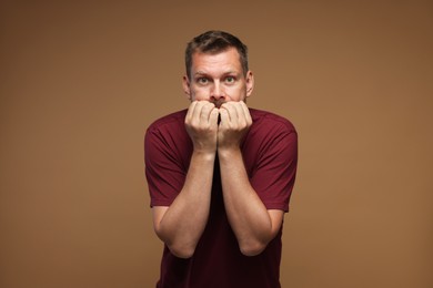 Photo of Man suffering from panic attack on brown background