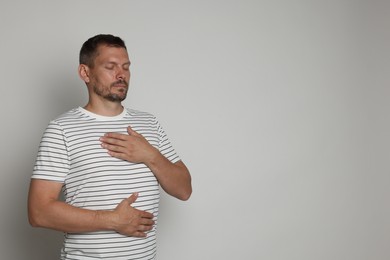 Photo of Panic attack. Man breathing to calm down on light grey background, space for text