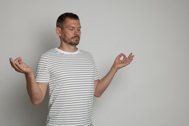 Photo of Panic attack. Man meditating to calm down on light grey background, space for text