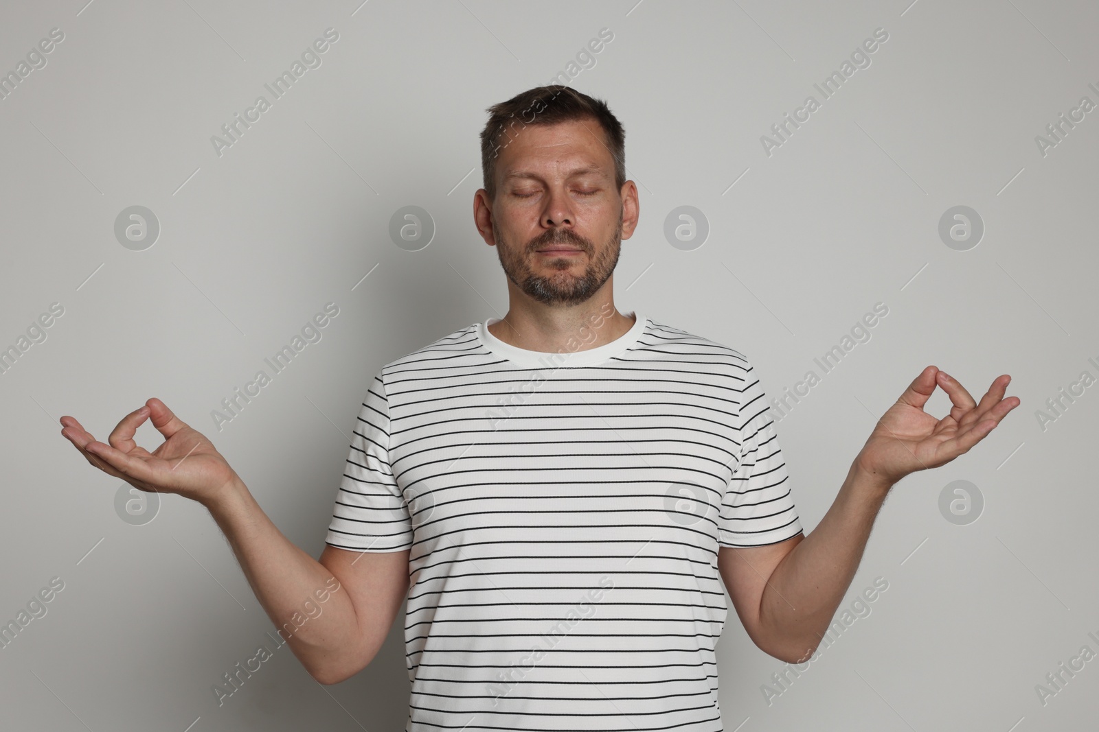 Panic attack. Man meditating to calm down on light grey background Photo of Panic attack. Man meditating to calm down on light grey background