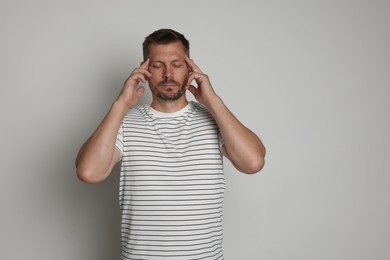 Photo of Panic attack. Man calming himself down on light grey background, space for text