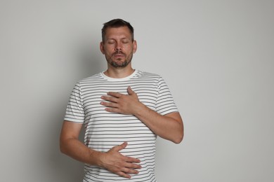 Photo of Panic attack. Man breathing to calm down on light grey background