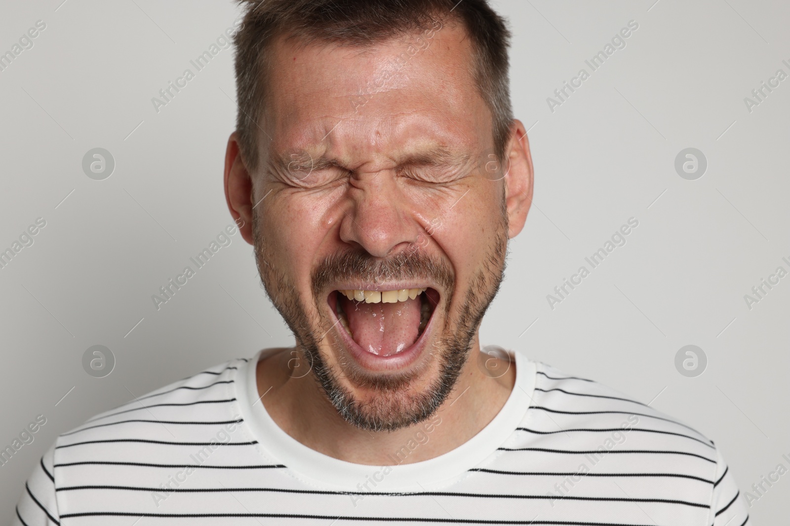 Man suffering from panic attack on light grey background Photo of Man suffering from panic attack on light grey background