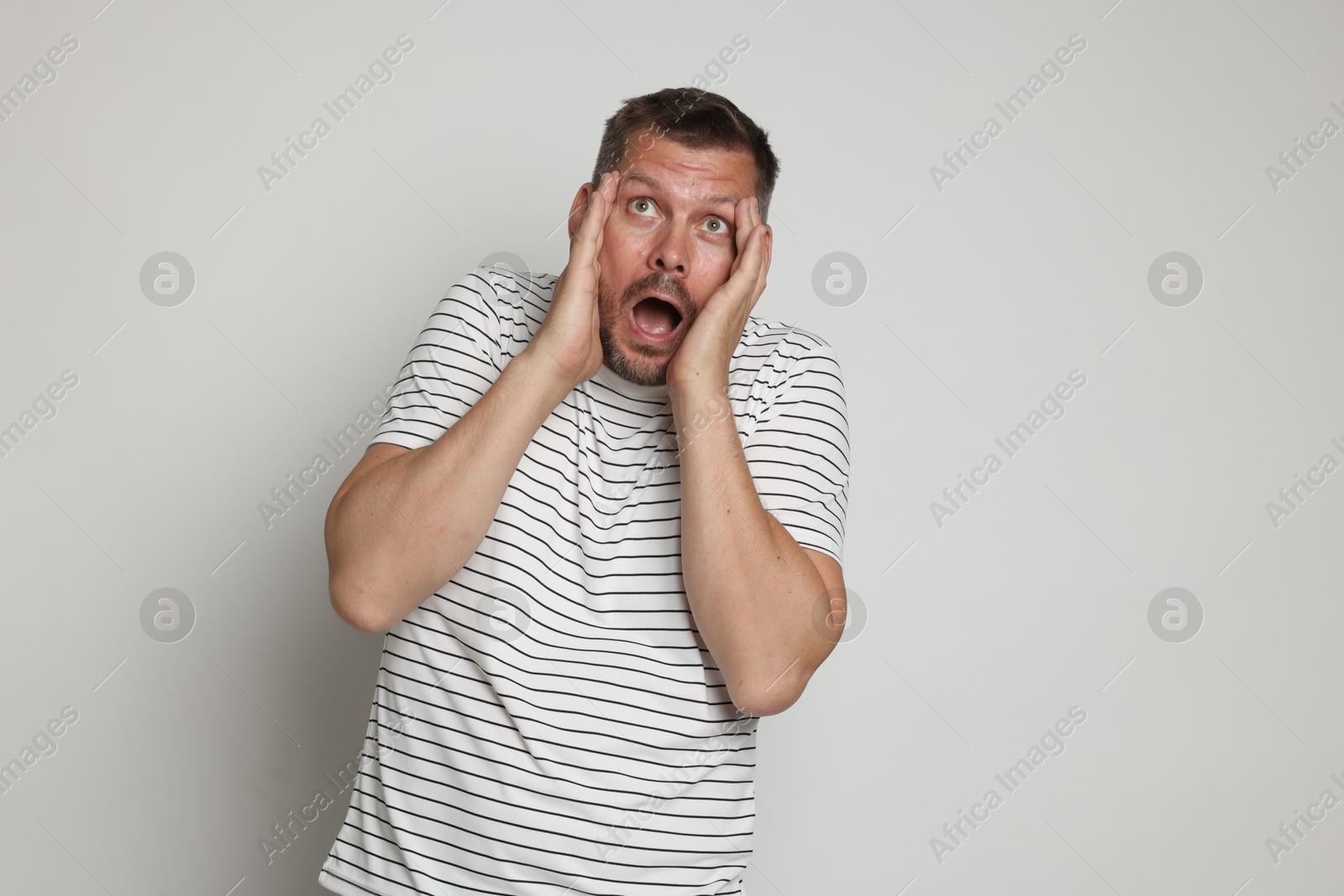 Man suffering from panic attack on light grey background Photo of Man suffering from panic attack on light grey background