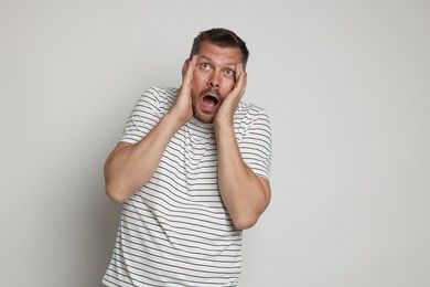 Photo of Man suffering from panic attack on light grey background
