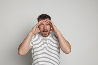 Photo of Man suffering from panic attack on light grey background