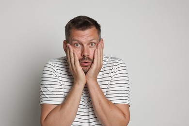 Photo of Man suffering from panic attack on light grey background