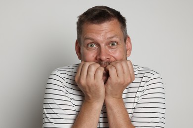 Photo of Man suffering from panic attack on light grey background