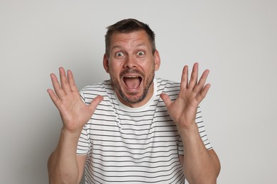 Photo of Man suffering from panic attack on light grey background