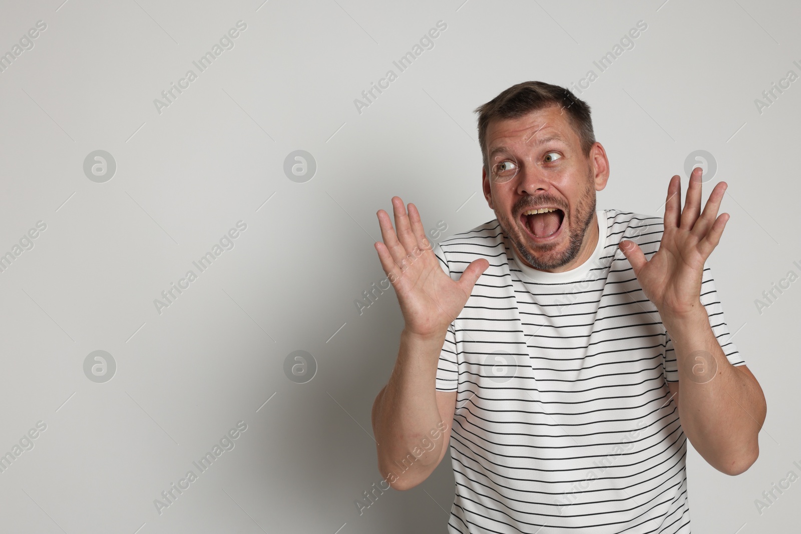 Man suffering from panic attack on light grey background, space for text Photo of Man suffering from panic attack on light grey background, space for text