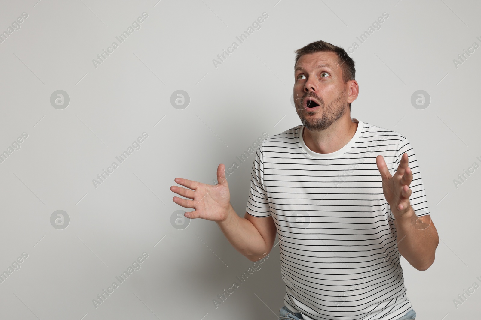 Man suffering from panic attack on light grey background, space for text Photo of Man suffering from panic attack on light grey background, space for text