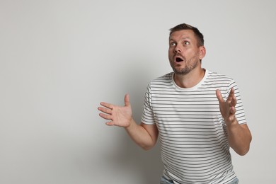 Photo of Man suffering from panic attack on light grey background, space for text