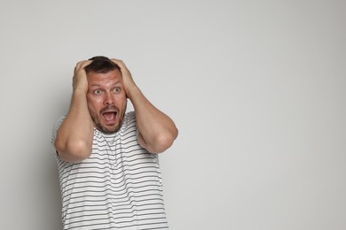 Photo of Man suffering from panic attack on light grey background, space for text