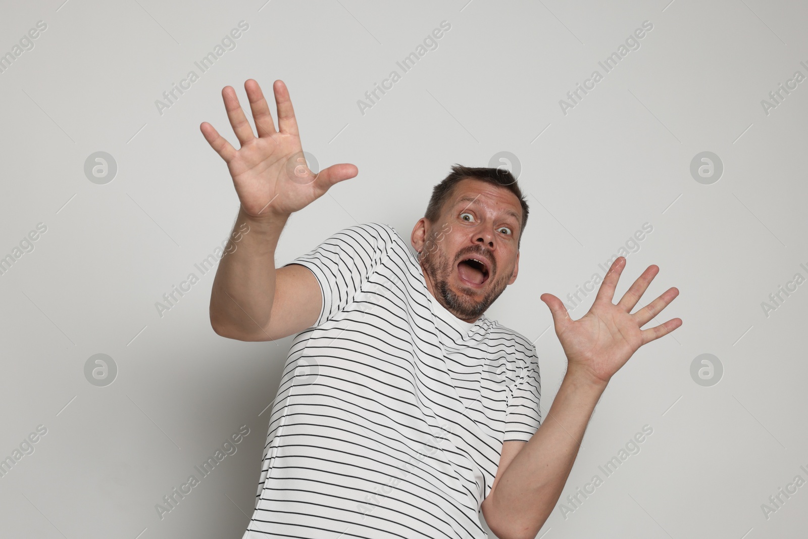 Man suffering from panic attack on light grey background Photo of Man suffering from panic attack on light grey background