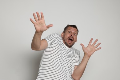 Photo of Man suffering from panic attack on light grey background