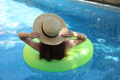 Photo of Girl on inflatable ring in swimming pool, back view
