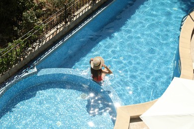 Photo of Beautiful girl with straw hat in outdoor swimming pool, above view