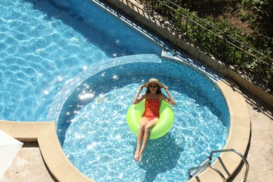 Photo of Beautiful girl on inflatable ring in swimming pool, above view