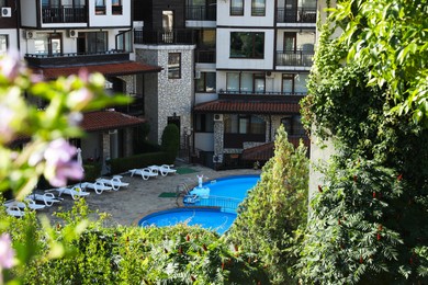Photo of Outdoor swimming pool, sunbeds and green plants near hotel at luxury resort