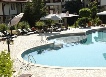 Photo of Outdoor swimming pool and sunbeds near hotel at luxury resort