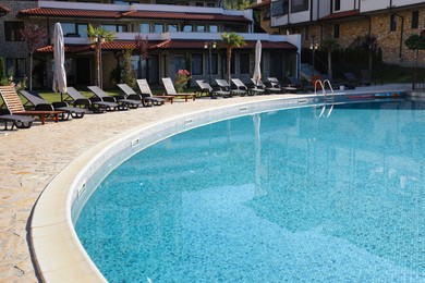 Photo of Outdoor swimming pool and sunbeds near hotel at luxury resort