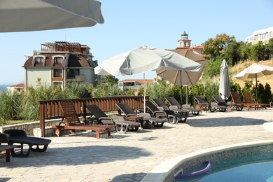 Photo of Sunbeds, umbrellas, buildings and green plants at luxury resort