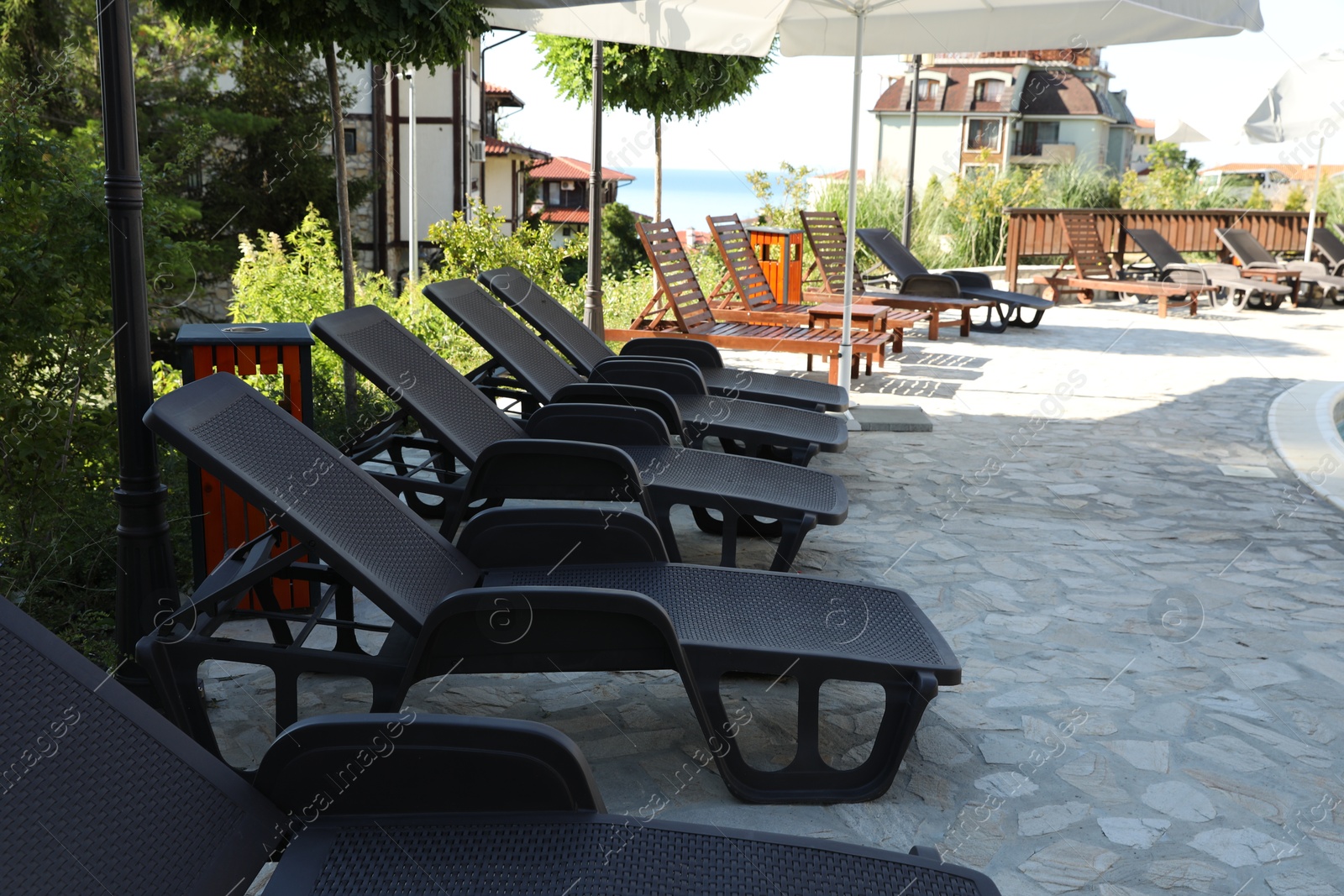 Photo of Sunbeds, umbrellas and green plants at luxury resort