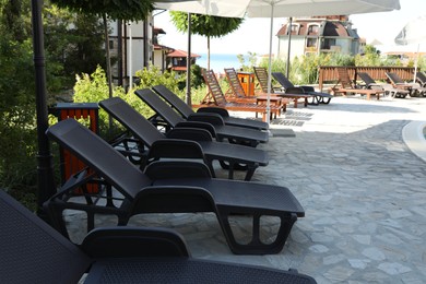 Photo of Sunbeds, umbrellas and green plants at luxury resort