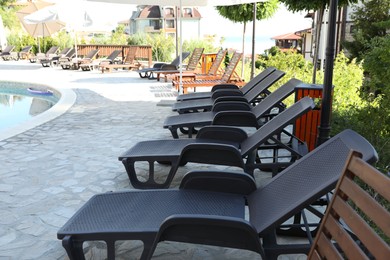 Photo of Sunbeds, umbrellas, swimming pool and green plants outdoors