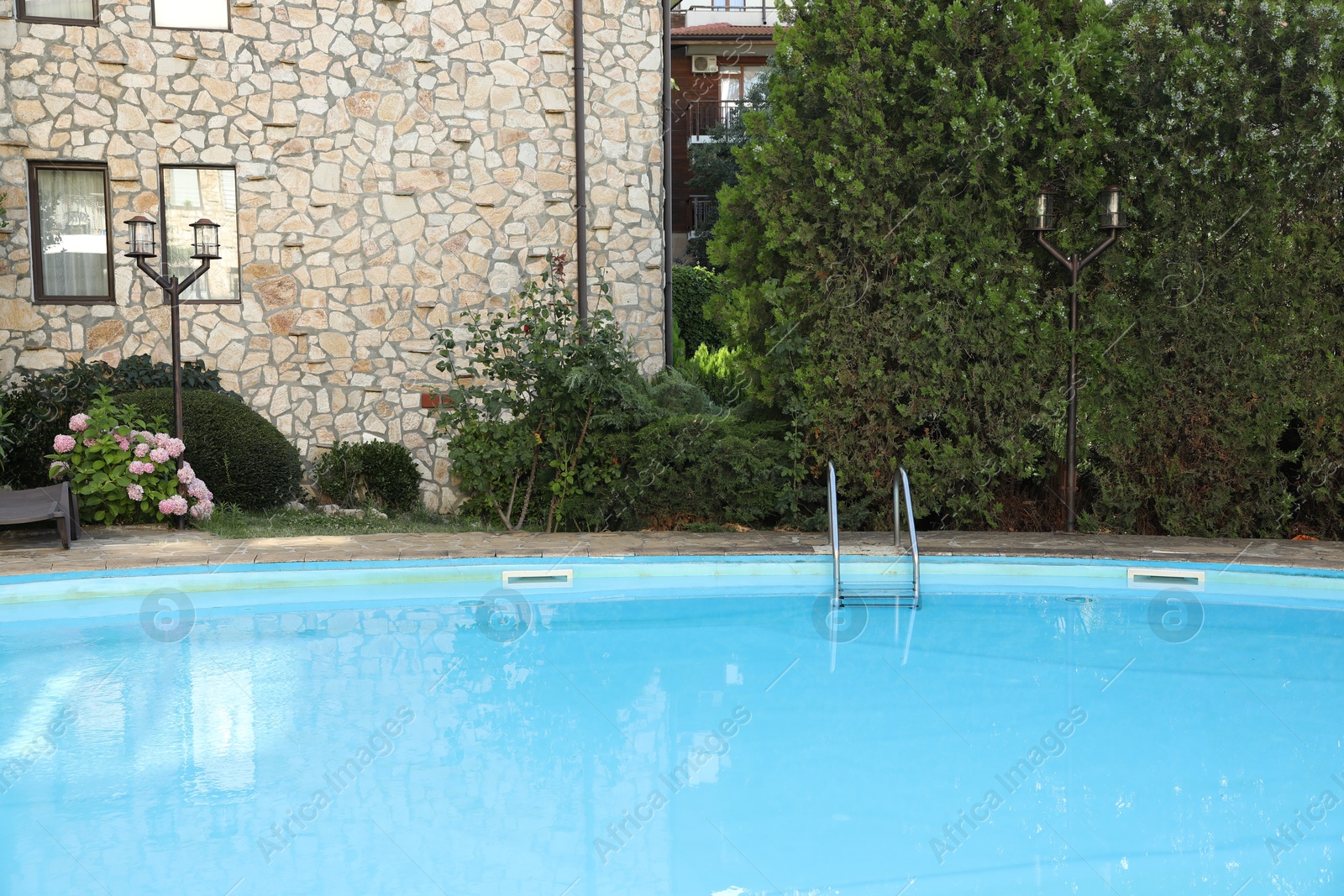 Photo of Outdoor swimming pool and green plants near hotel at luxury resort