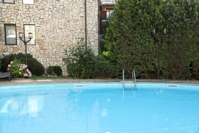 Photo of Outdoor swimming pool and green plants near hotel at luxury resort