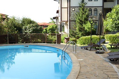 Photo of Outdoor swimming pool, sunbeds and green plants at luxury resort