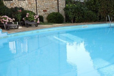 Photo of Outdoor swimming pool, sunbeds and green plants near hotel at luxury resort
