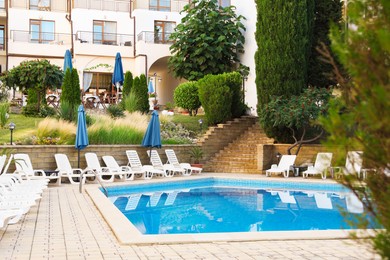 Photo of Outdoor swimming pool and sunbeds near hotel at luxury resort