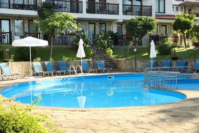 Photo of Outdoor swimming pool and sunbeds near hotel at luxury resort